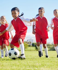 Soccer, ball or sports and a girl team training or playing together on a field for practice. Fitness, football and grass with kids running or dribbling on a pitch for competition or exercise.